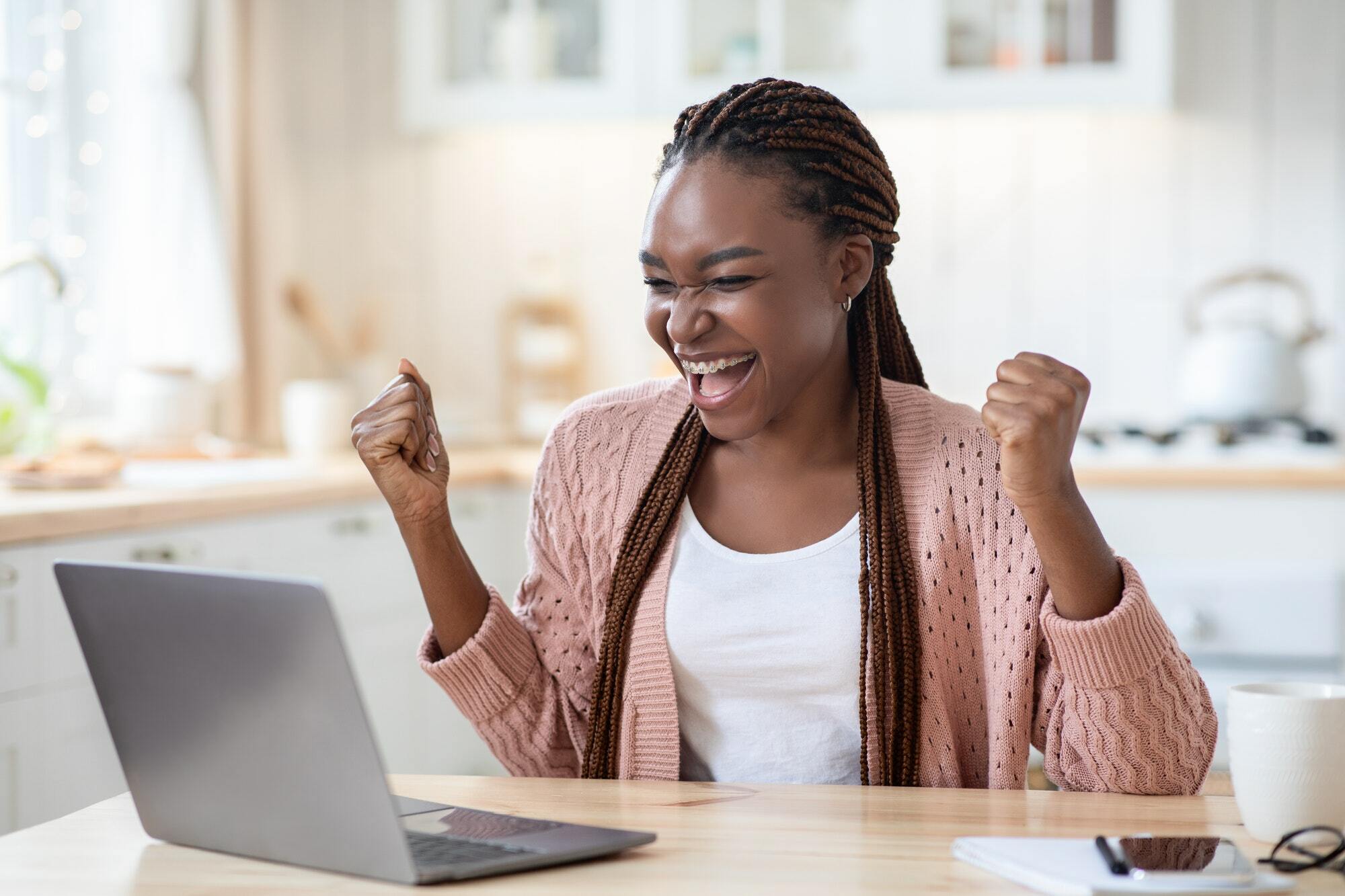 Overjoyed African American Lady Celebrating Success With Laptop At Home,